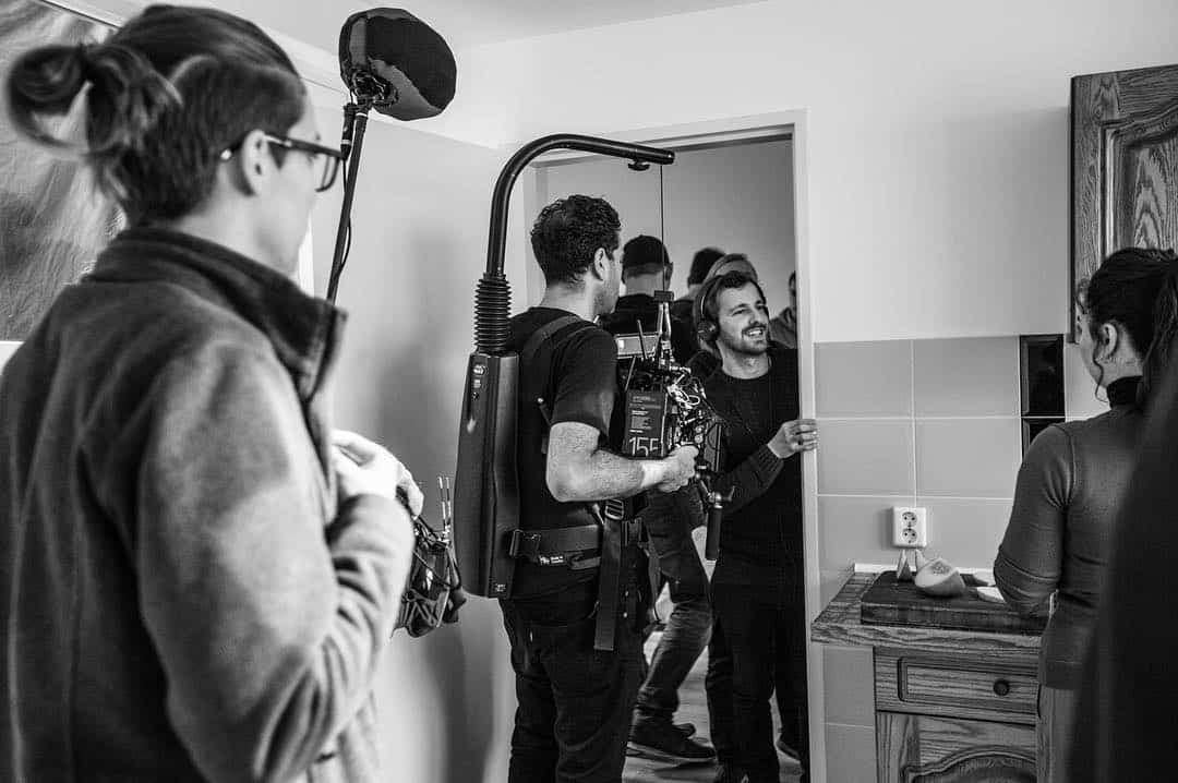 Film crew capturing a scene with professional equipment in a home environment.