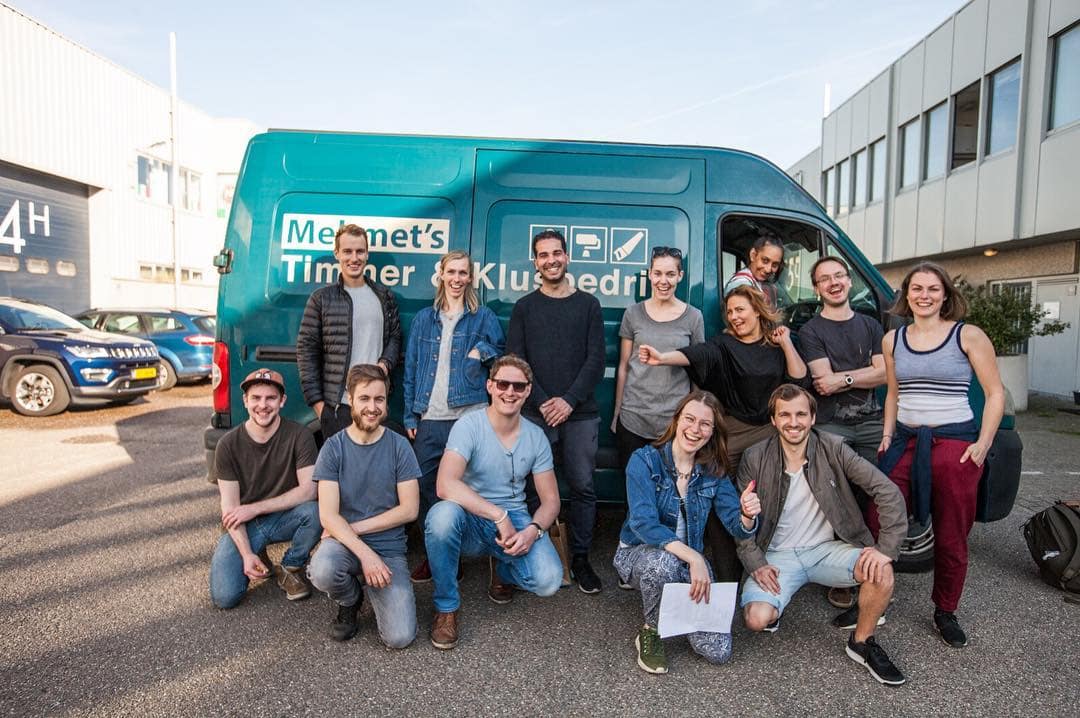 Group of young professionals in front of a Waves video agency van outdoors.