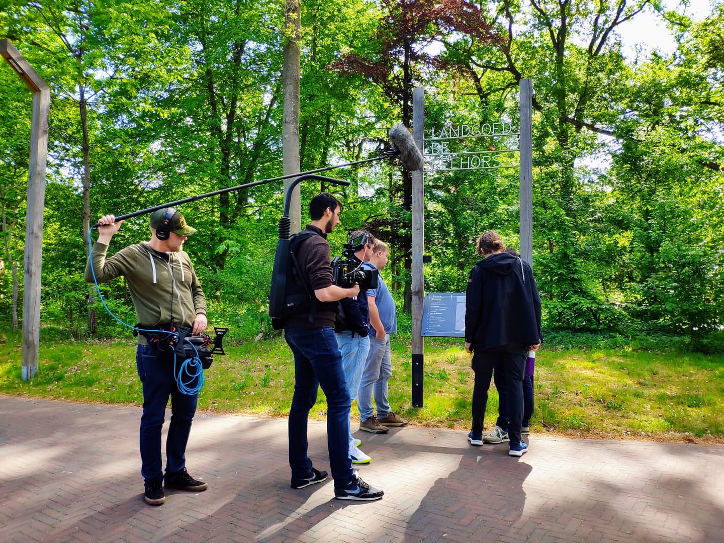 Creative team filming outdoors in a lush green park setting.