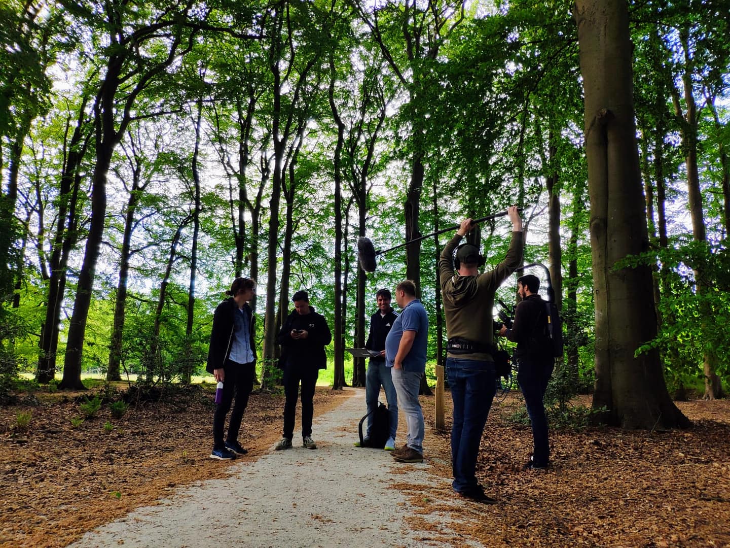 Group of videographers filming in a lush green forest setting.
