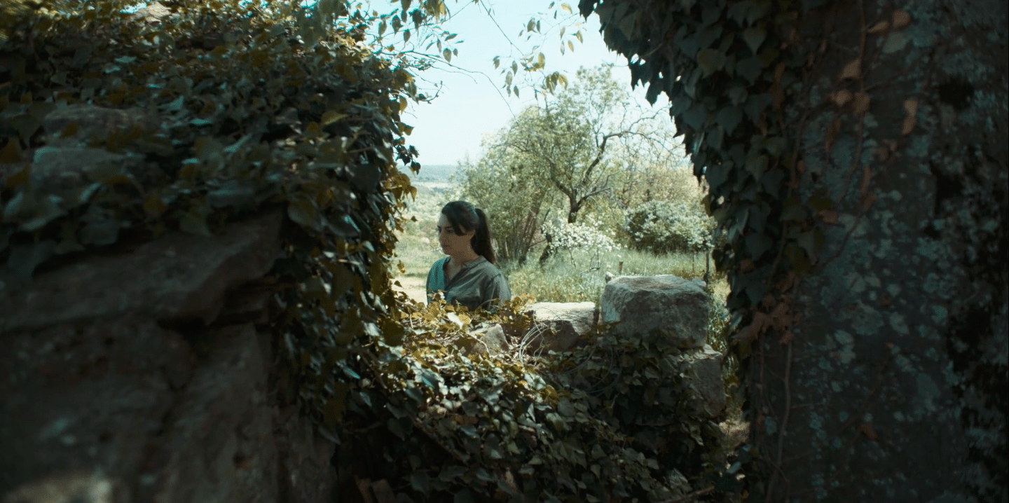 Woman filming outdoors through natural frame.