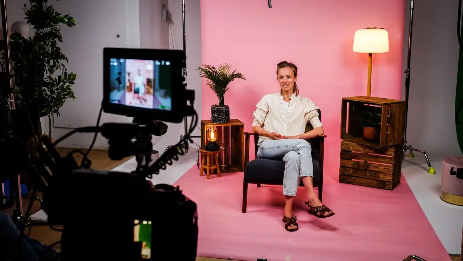 Woman filming professional video in studio with pink background and lighting.