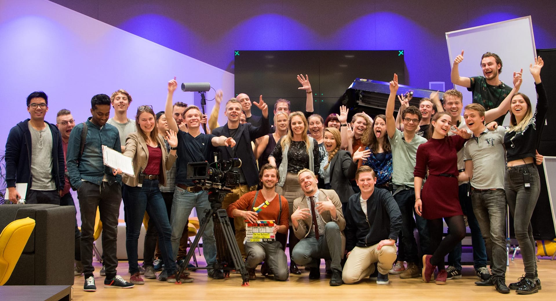 Group of diverse people celebrating with raised hands and smiles in a studio setting.