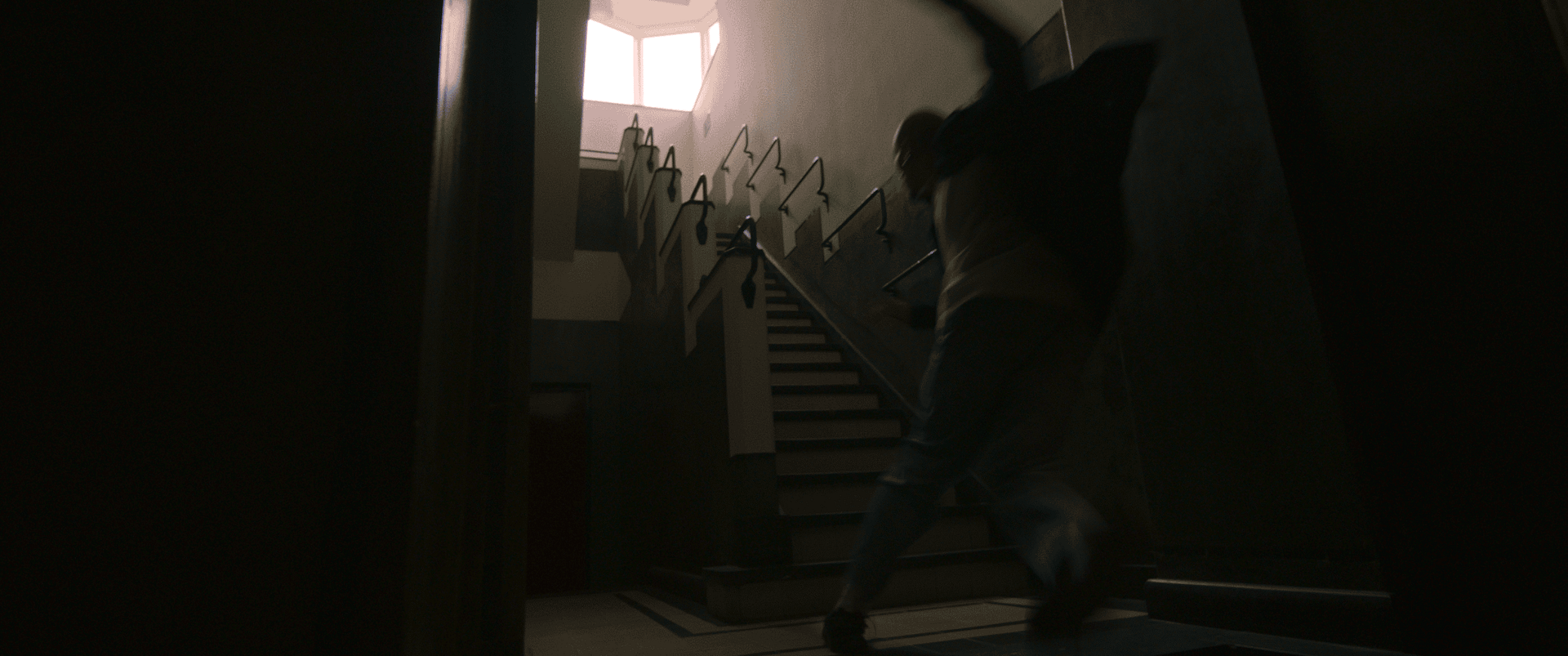 Person walking up a staircase in a dimly lit building interior.