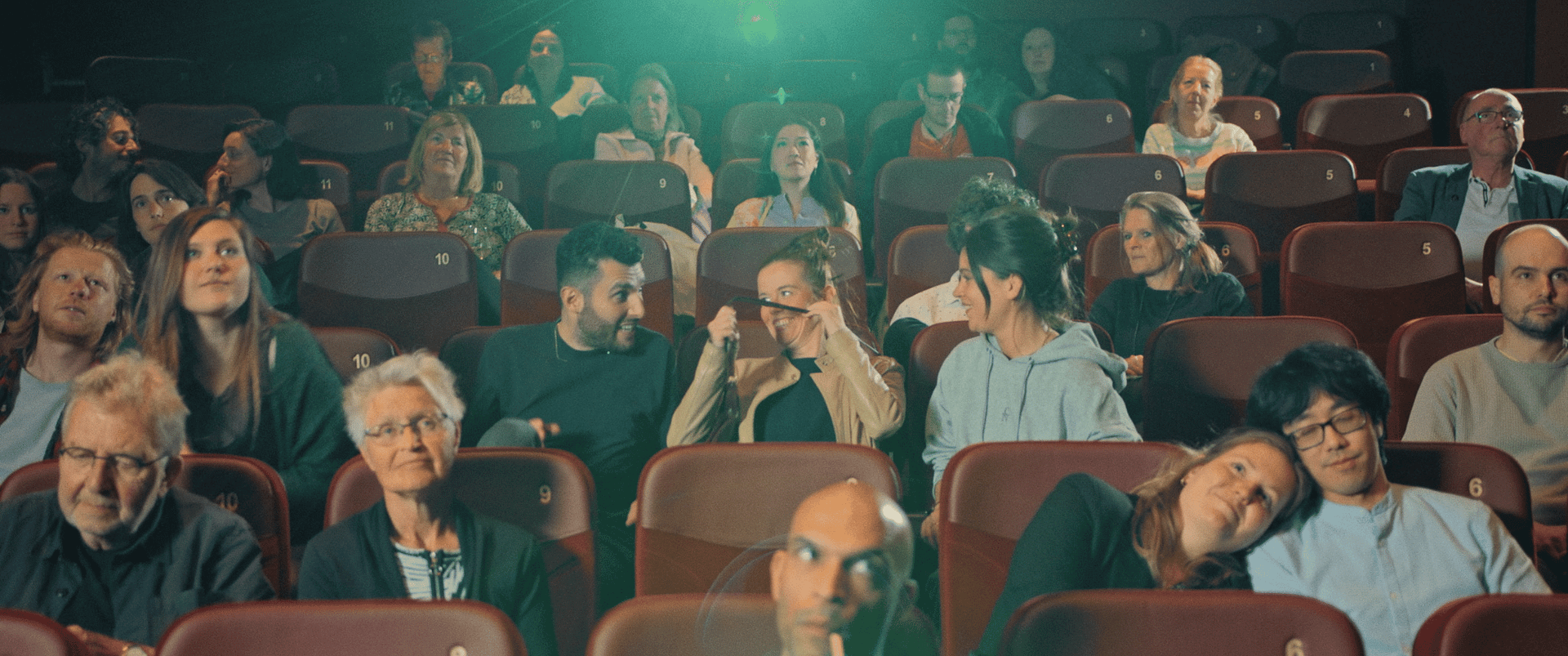 Audience watching a presentation in a theater setting, showcasing video production expertise.