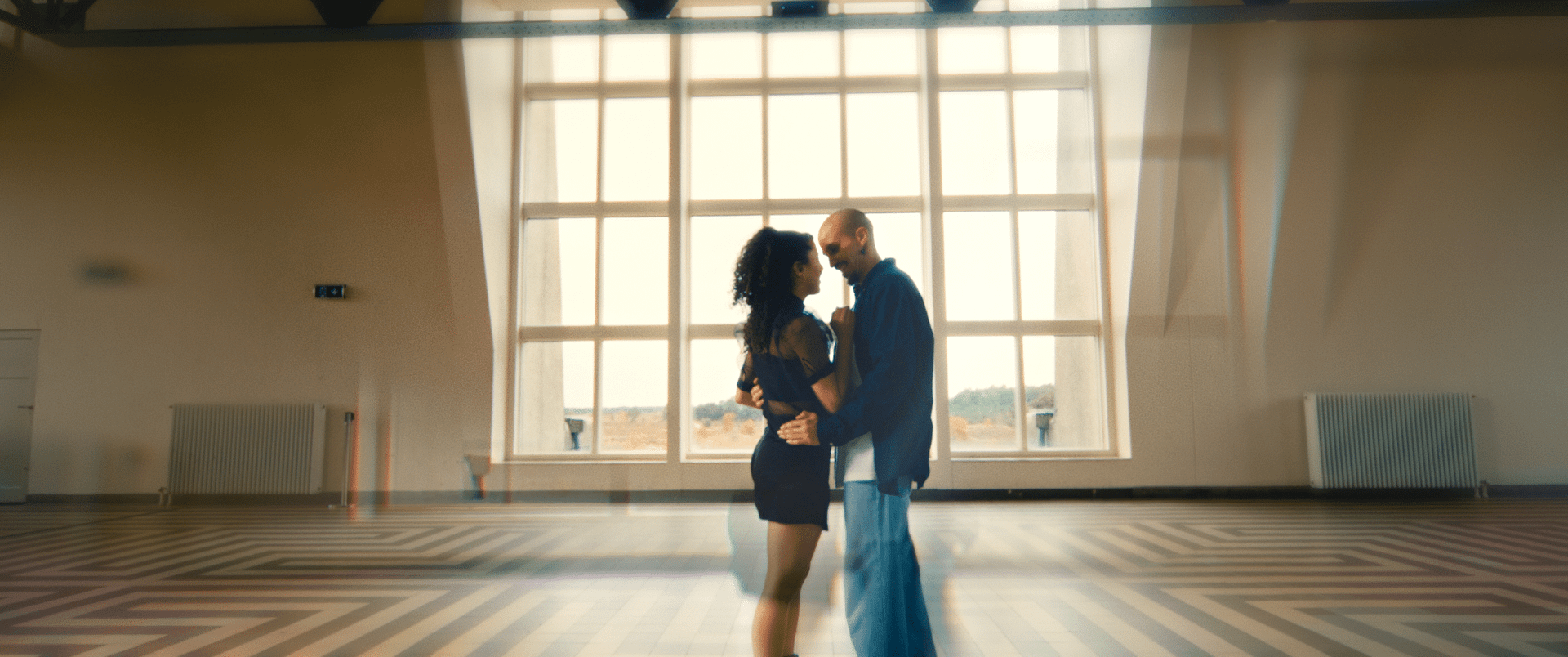 Couple dancing in a spacious studio with large windows, capturing a creative and dynamic atmosphere.