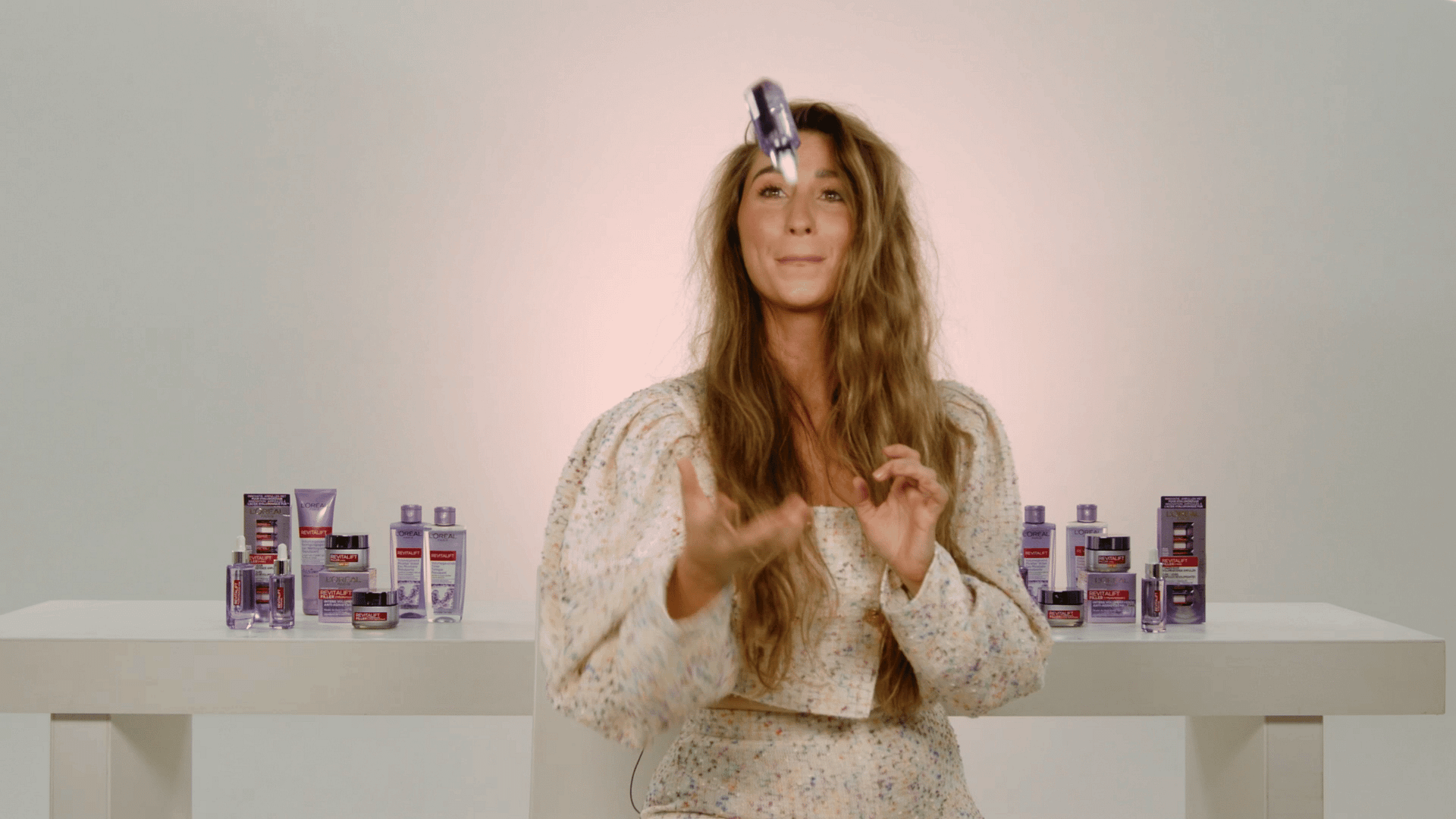 A woman presenting skincare products in a professional setting, emphasizing branding and product sho.