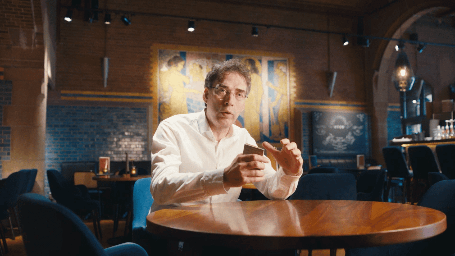 Man using smartphone in a modern, stylish cafe or coworking space.