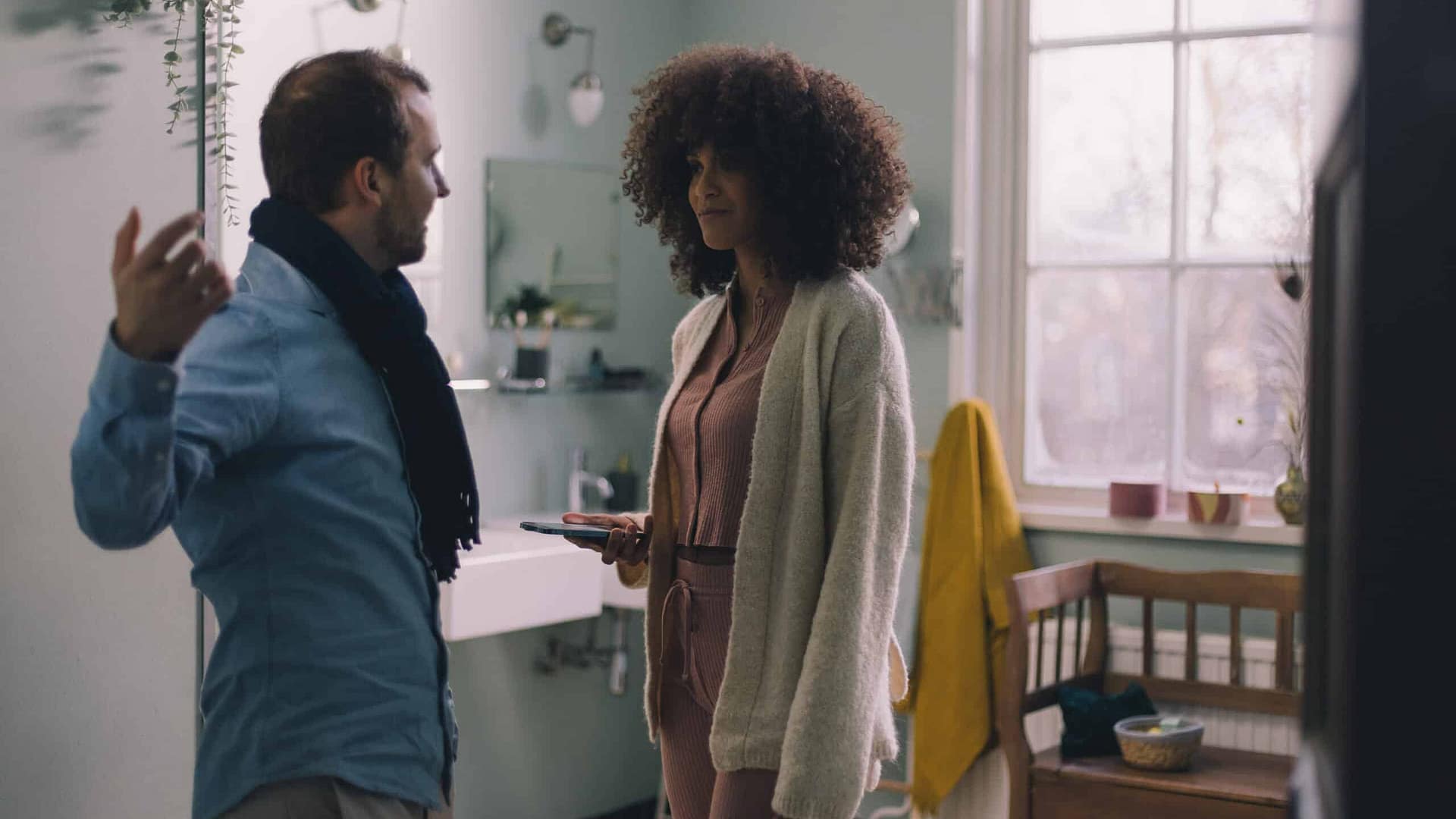 Two people having a conversation in a modern, well-lit kitchen.