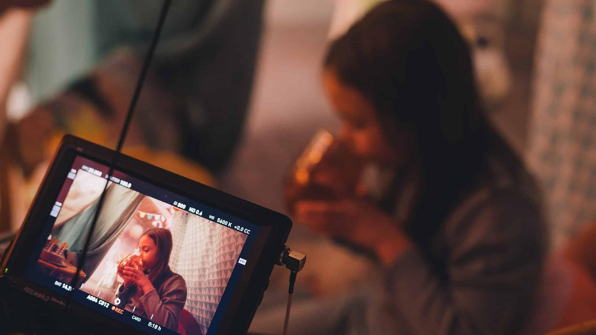 Creative video production team filming a woman in a cozy indoor setting.
