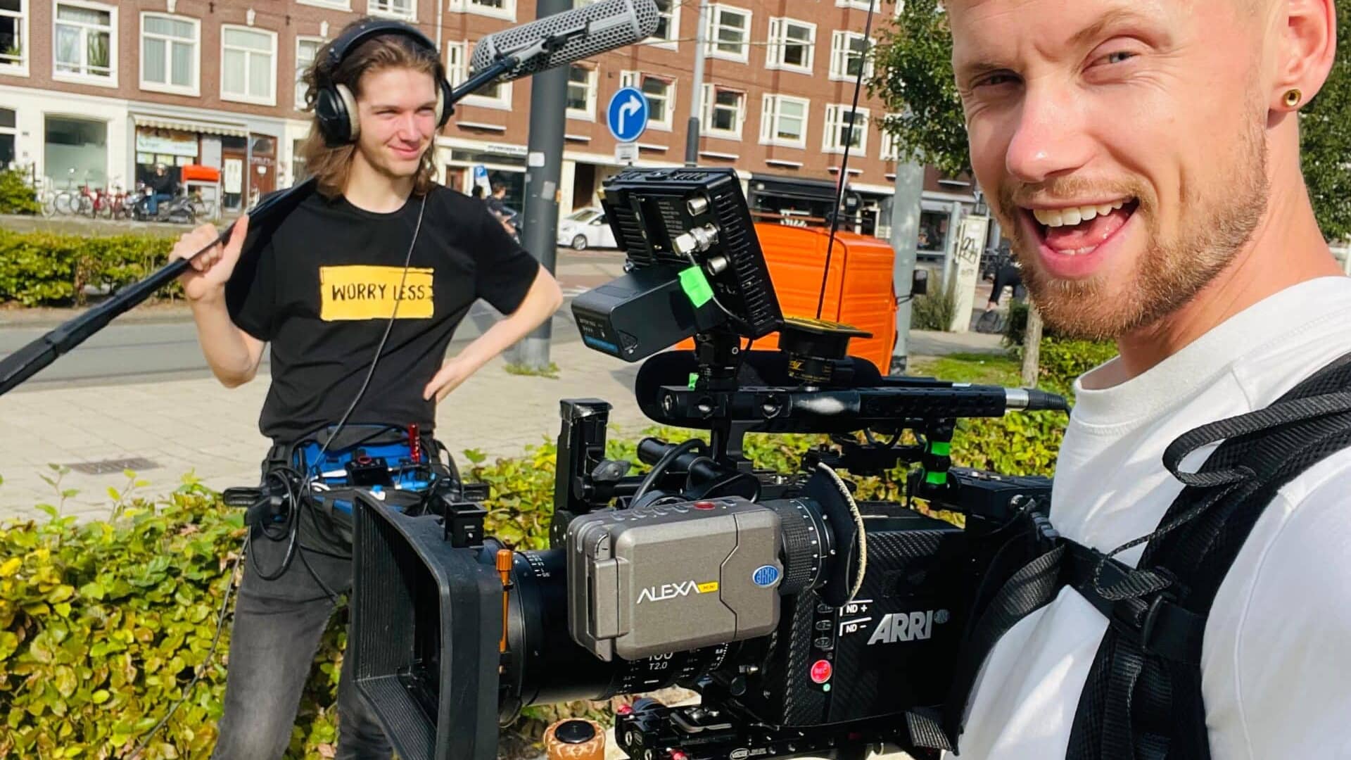 Filmmakers filming outdoor scene with professional camera equipment in urban setting.