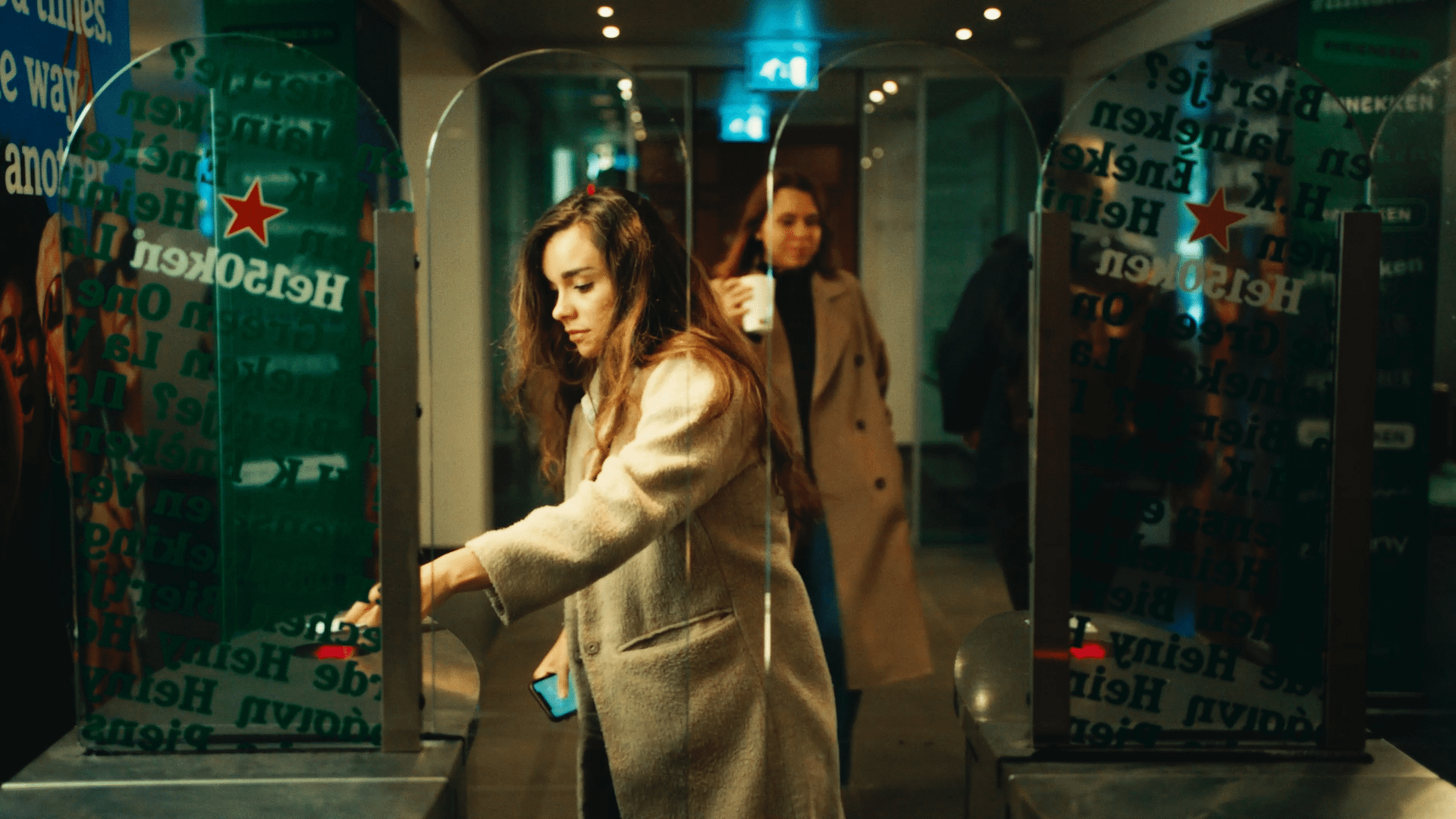 Young woman using an ATM at night in an urban setting.