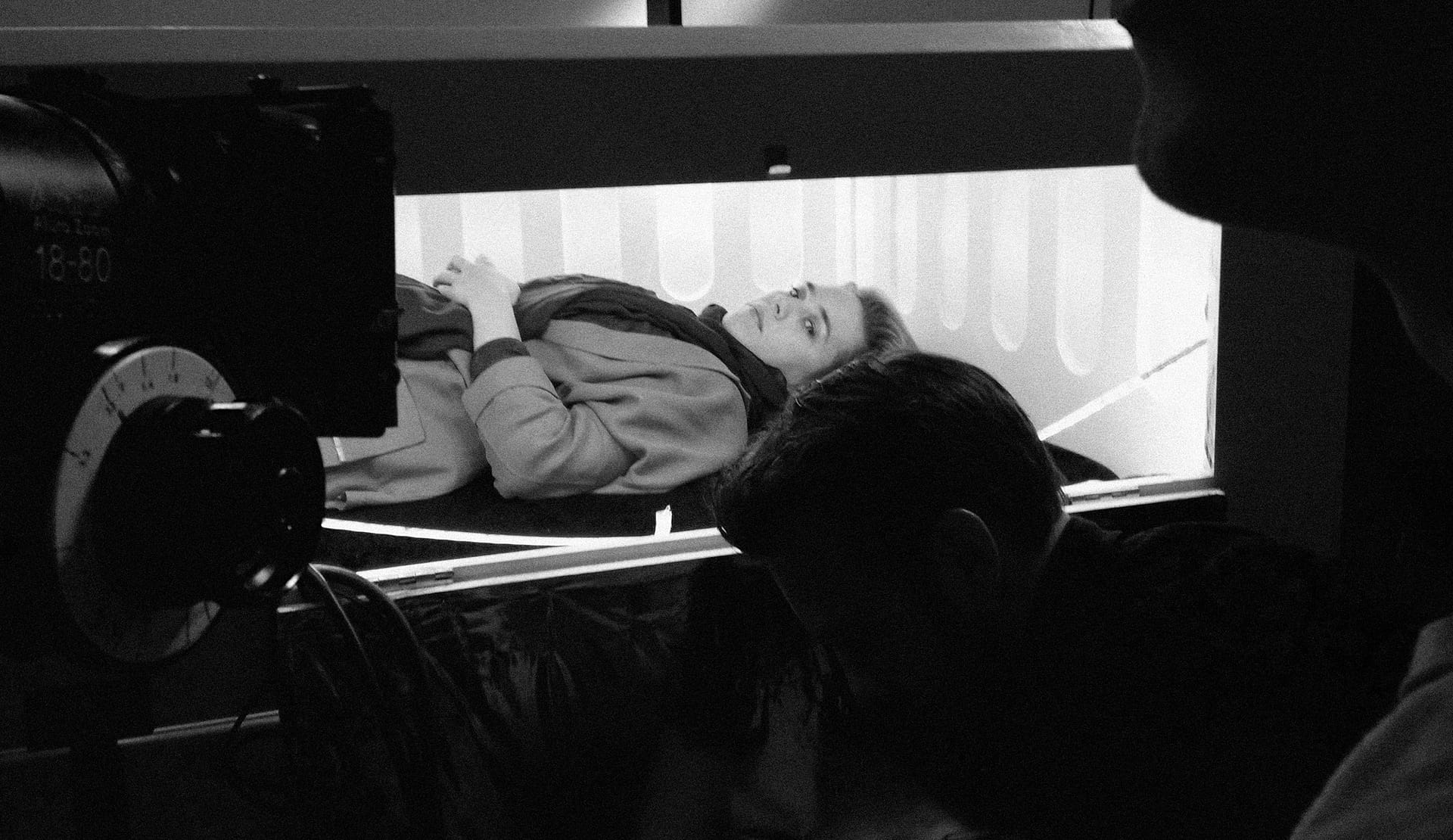 Filmmakers filming a scene with a woman lying on a bed, behind the camera, in a professional video s.