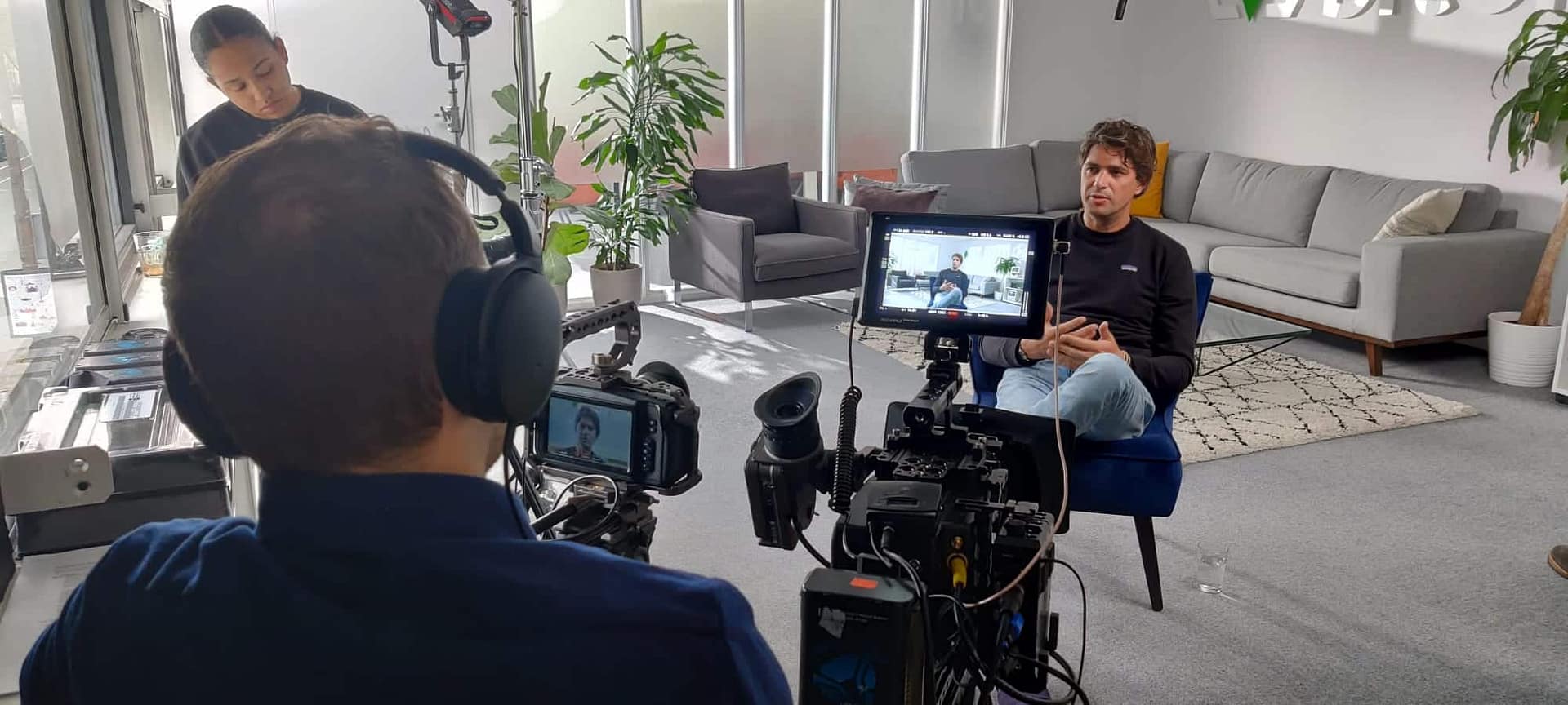 Filmmaker recording interview in modern office setting for video project.