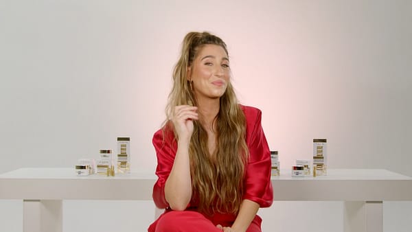 Woman with glowing skin testing L'Oréal Paris skincare products.