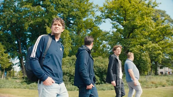 Group of young men walking outdoors in a park, casual style, sunny day.