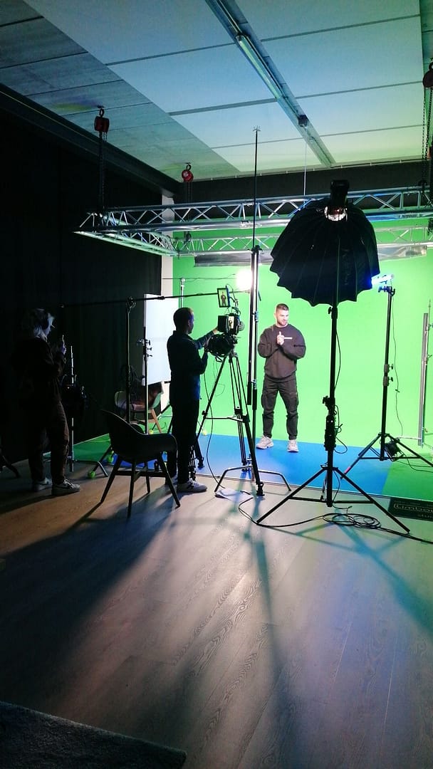 Professional video shoot with green screen and lighting setup in studio.
