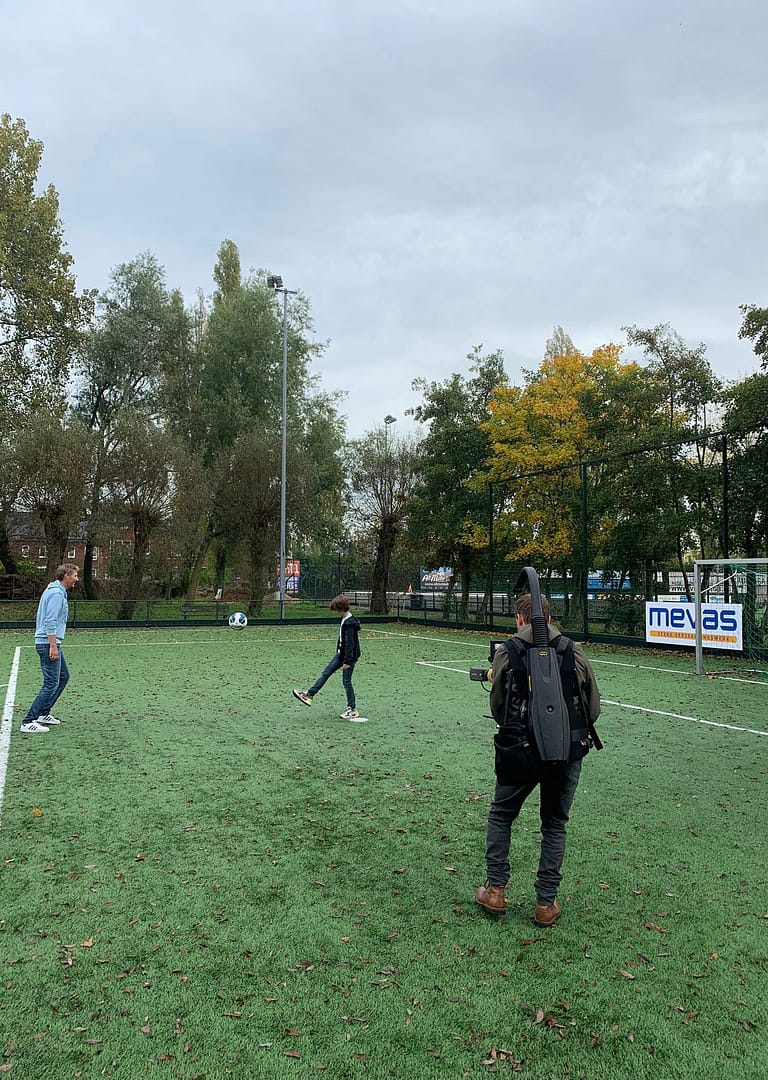 People playing soccer on a field with trees in the background.