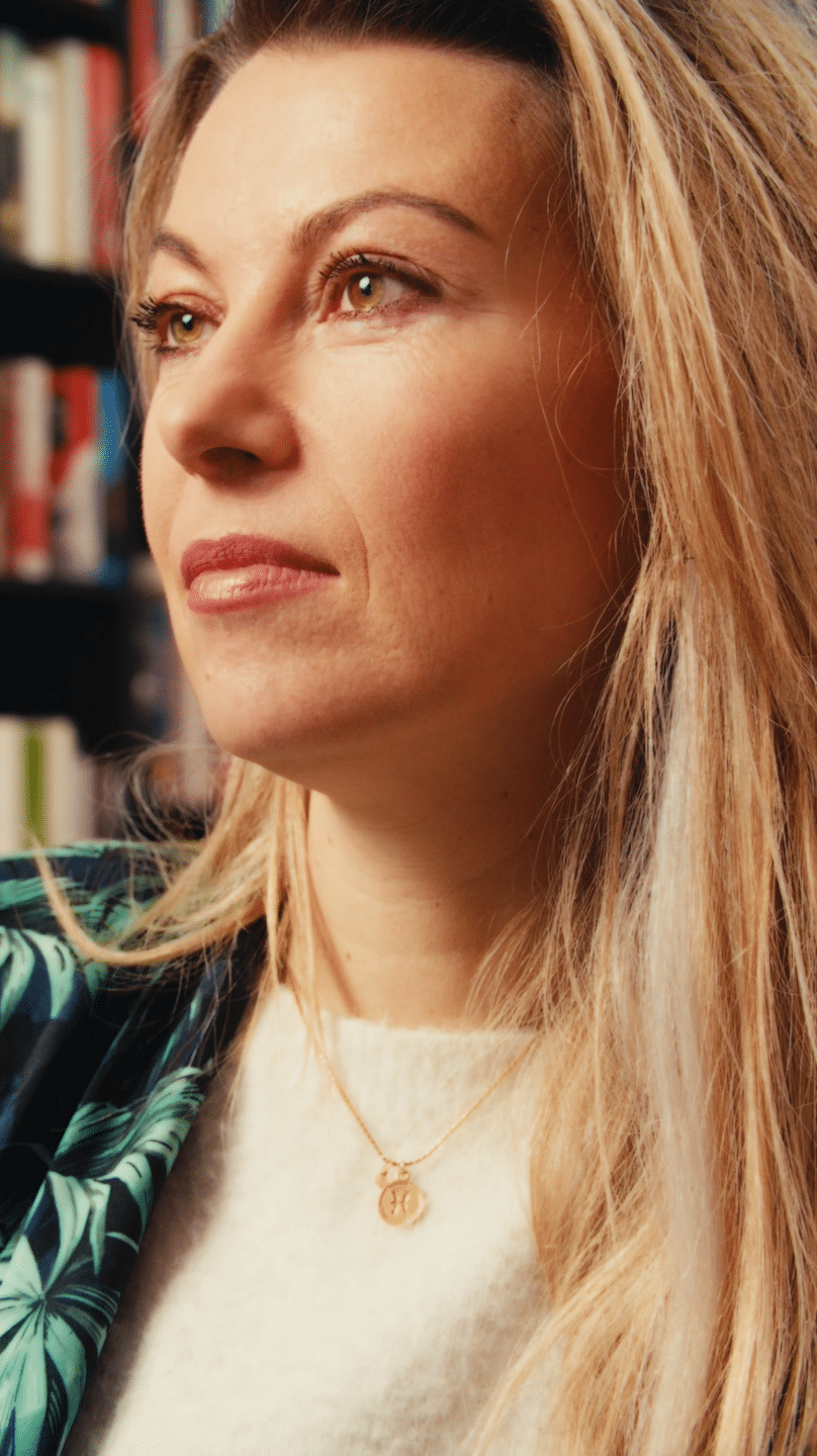 Close-up of a woman with blonde hair, looking thoughtfully, in a creative workspace.