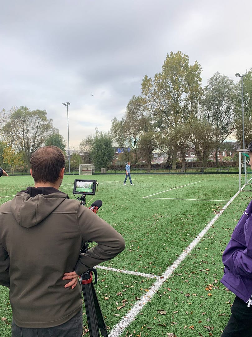 Video production outdoor sports field with camera operator filming athlete.