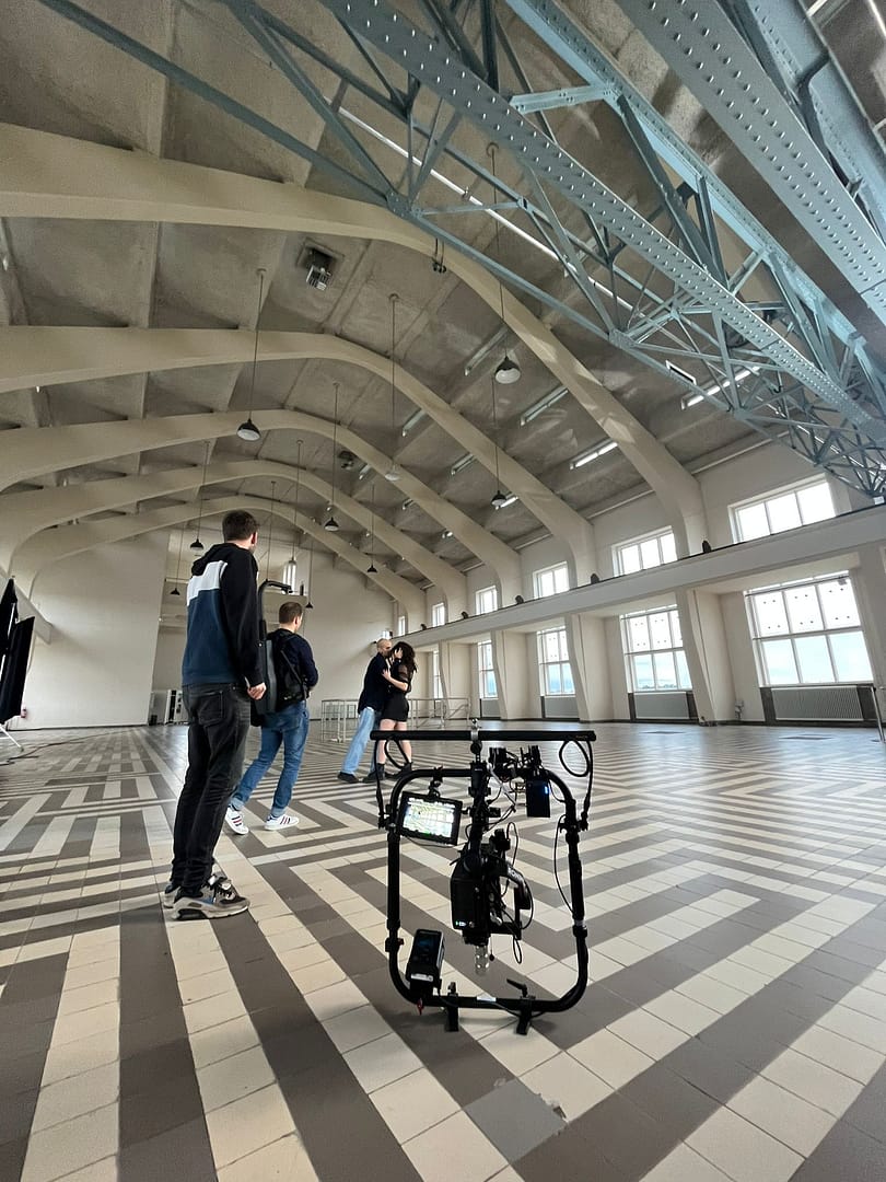Interior of a spacious studio with a camera stabilizer and people preparing for filming.