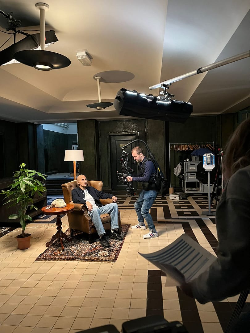 Professional video shoot capturing a seated interview with a camera operator and crew.