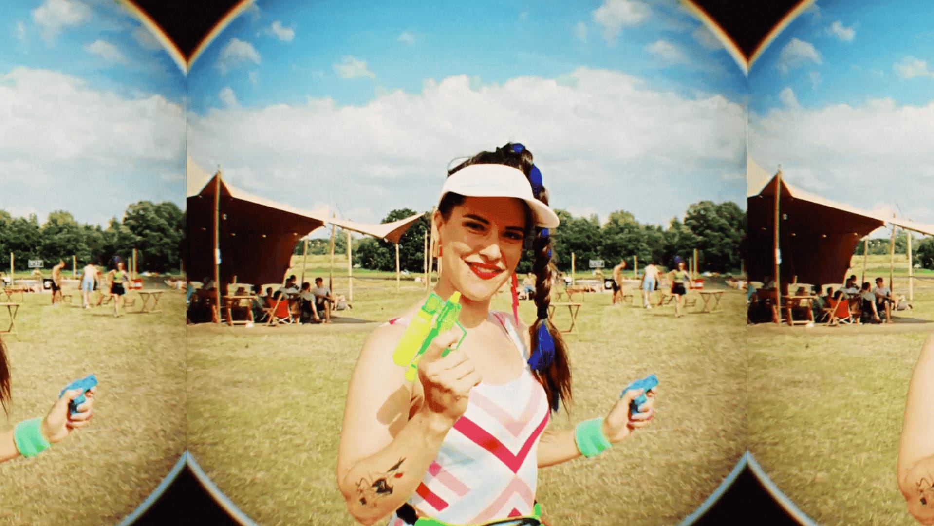 Woman at outdoor festival holding a green toy, smiling, with a sunny sky.